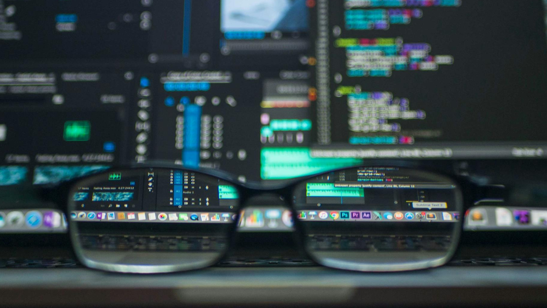 Eine Brille vergrößert Code von Monitoren dahinter